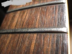 This picture shows very rough frets. A great exaggeration of most fret jobs, but even a minute level of this kind of wear will greatly influence the smoothness and playability. 